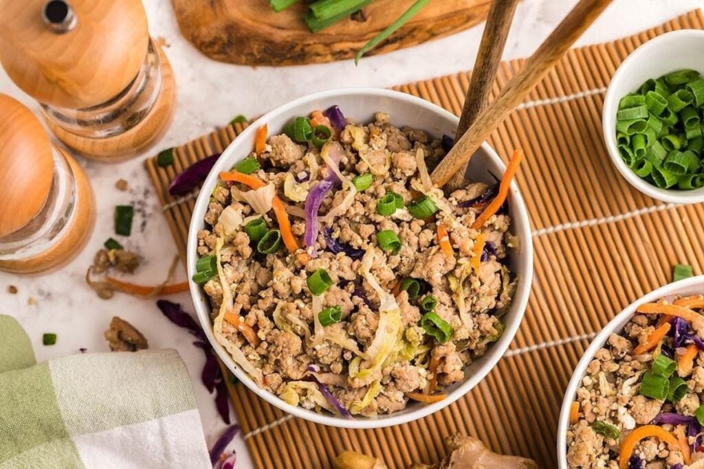 A deconstructed egg roll made of ground pork, cabbage and carrots in a bowl.