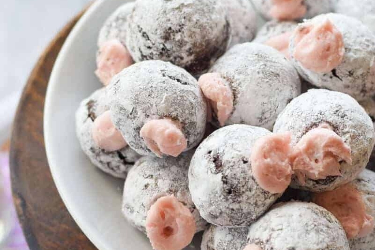 A plate of chocolate covered cookies with pink sprinkles.